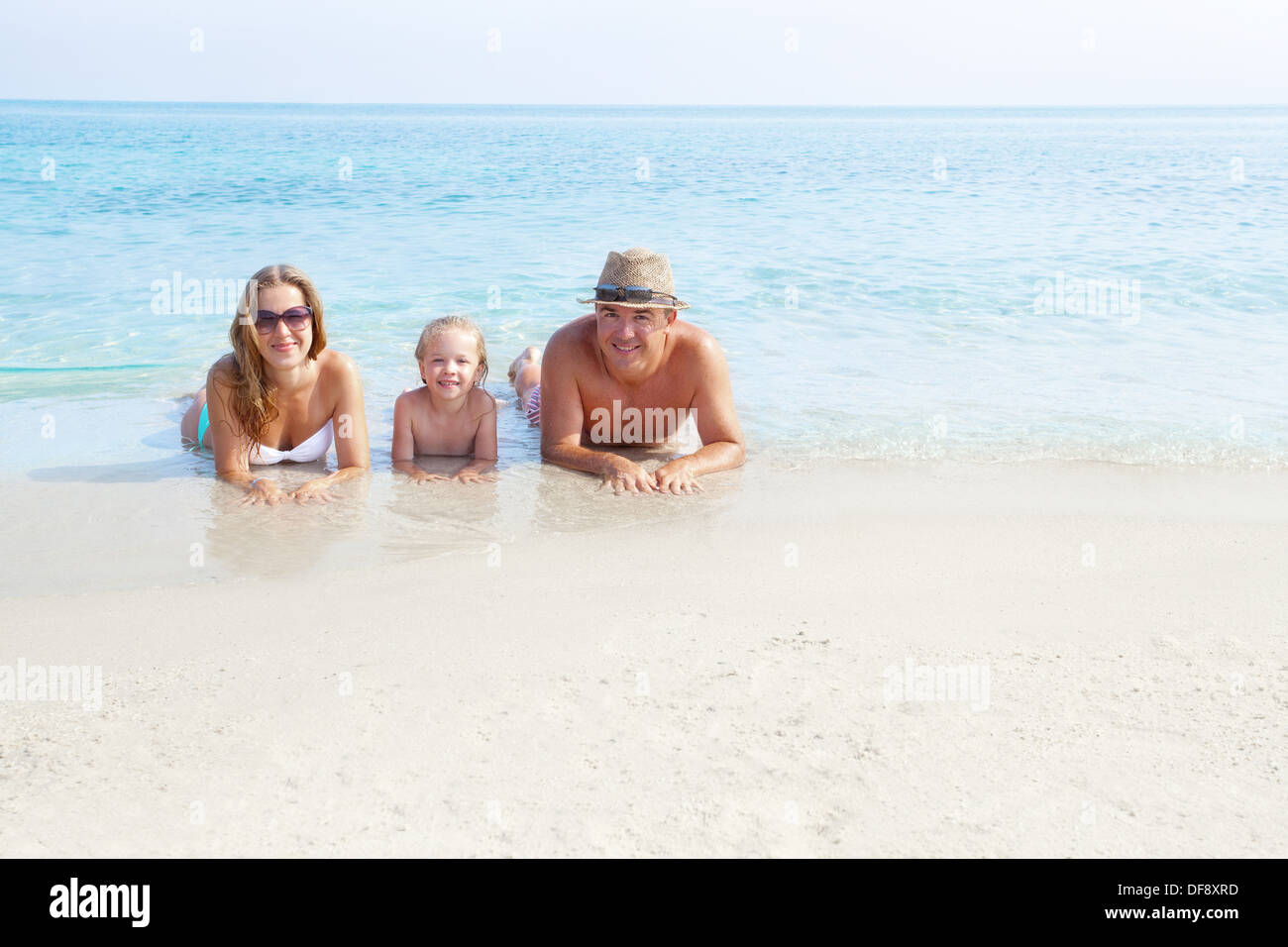 La famiglia felice la posa sulla sabbia godendo l'oceano Foto Stock