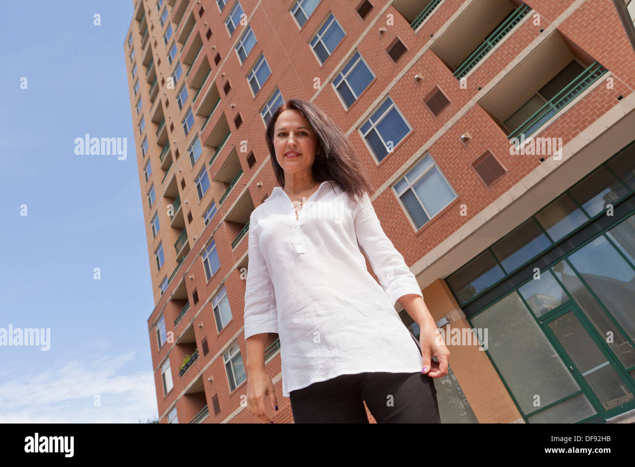 Di mezza età donna caucasici in piedi nella parte anteriore dell'edificio Foto Stock