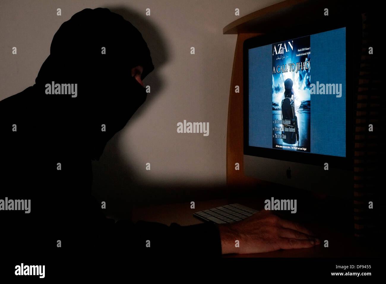Incappucciato e uomo mascherato guardando il terrorista azan rivista on line sul suo computer Foto Stock