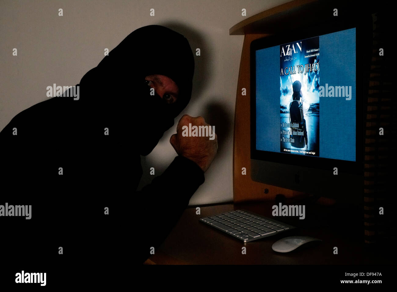 Incappucciato e uomo mascherato guardando il terrorista azan rivista on line sul suo computer Foto Stock