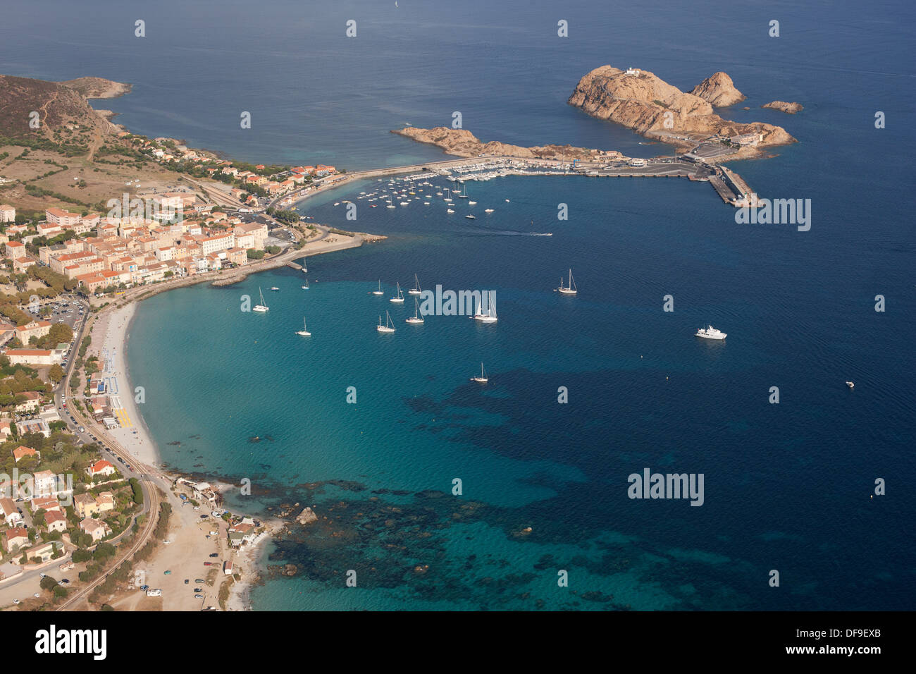 VISTA AEREA. Città di Île Rousse con la sua città vecchia, spiagge, porto turistico e terminal dei traghetti. Corsica, Francia. Foto Stock