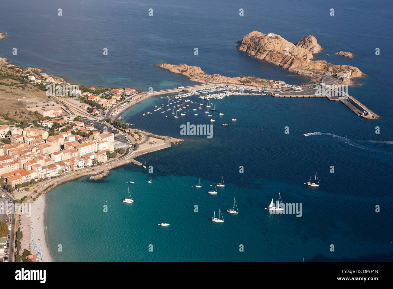 VISTA AEREA. Città di Île Rousse con la città vecchia e il molo che la collega ad un'isola rocciosa utilizzata come terminal dei traghetti. Corsica, Francia. Foto Stock