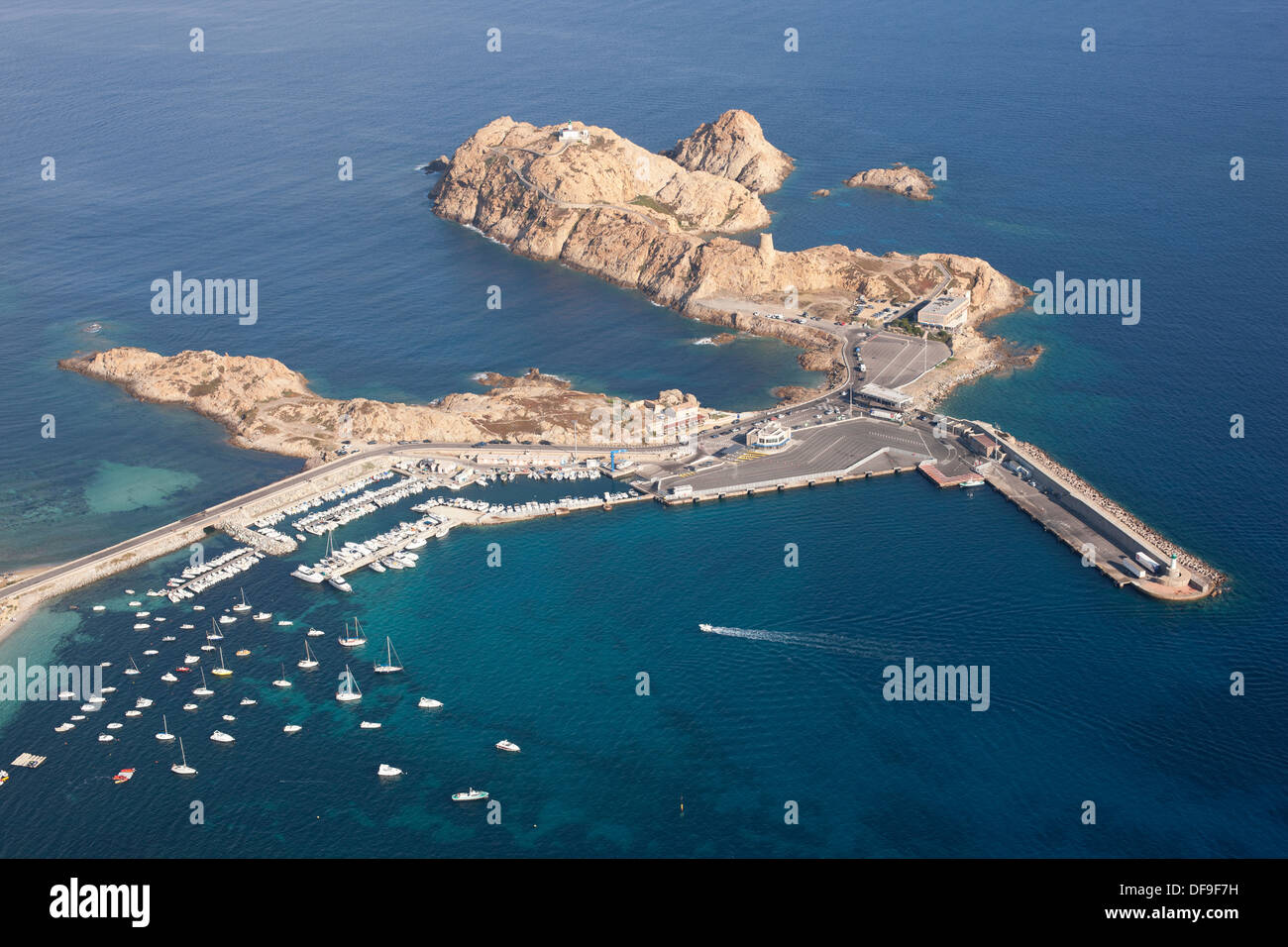 VISTA AEREA. Isola di pietra con il suo terminal dei traghetti e la strada che conduce al centro storico di l'Île Rousse. Haute-Corse, Corsica, Francia. Foto Stock