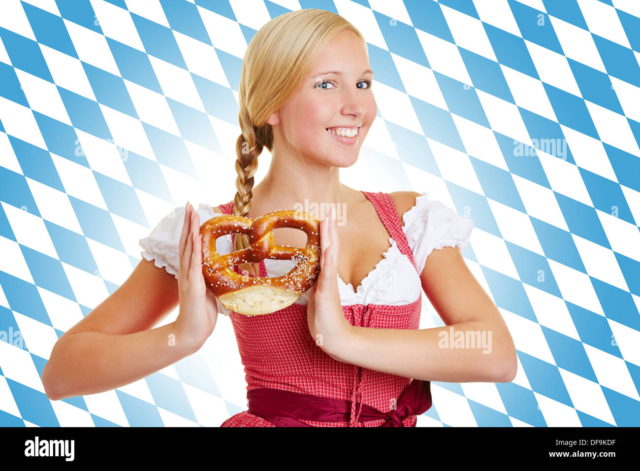 Sorridente donna attraente con pretzel in un grembiule davanti della bandiera bavarese Foto Stock