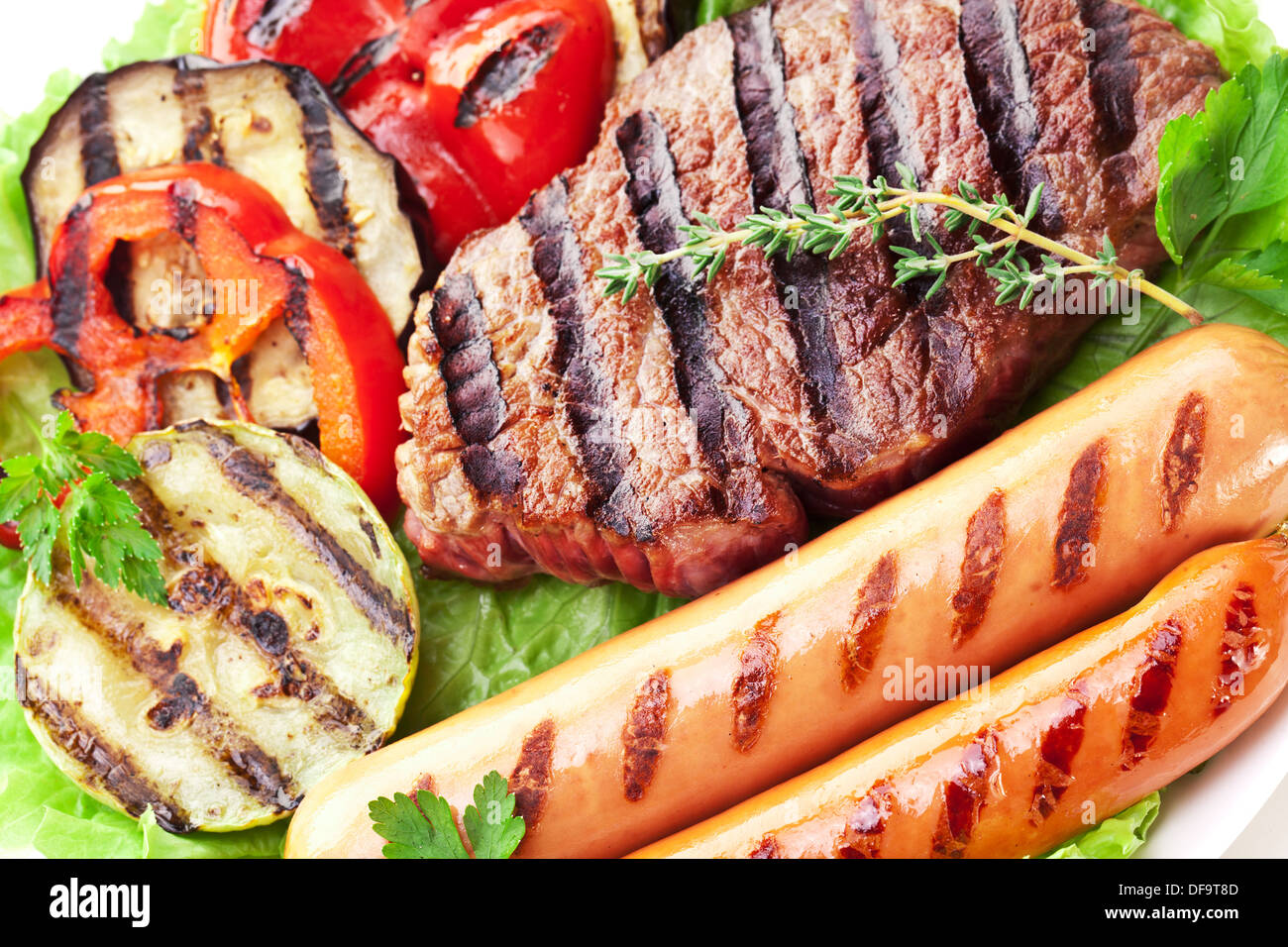 Bistecca alla griglia,salsicce e verdure sopra le foglie di lattuga. Foto Stock