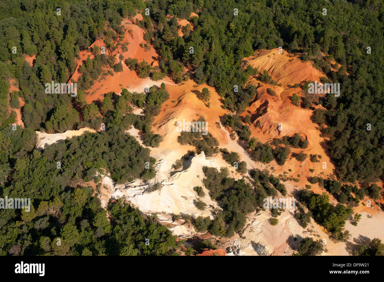 VISTA AEREA. Cava di ocra rossa in netto contrasto con il verde circostante fogliame. Rustrel, Lubéron, Vaucluse, Provenza, Francia. Foto Stock