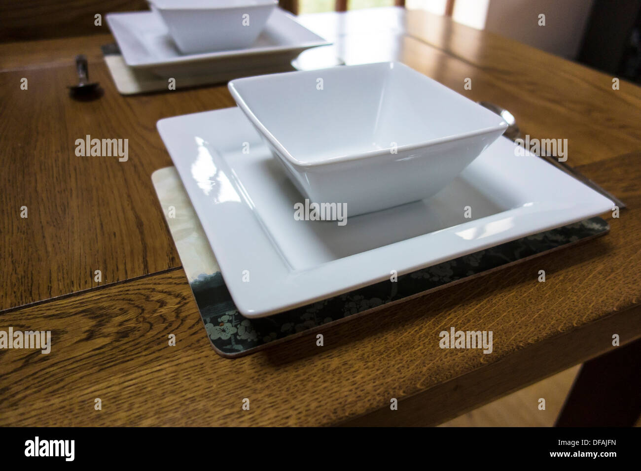 Impostazione del luogo per due persone.Bianco quadrato ciotole e piatti. Foto Stock