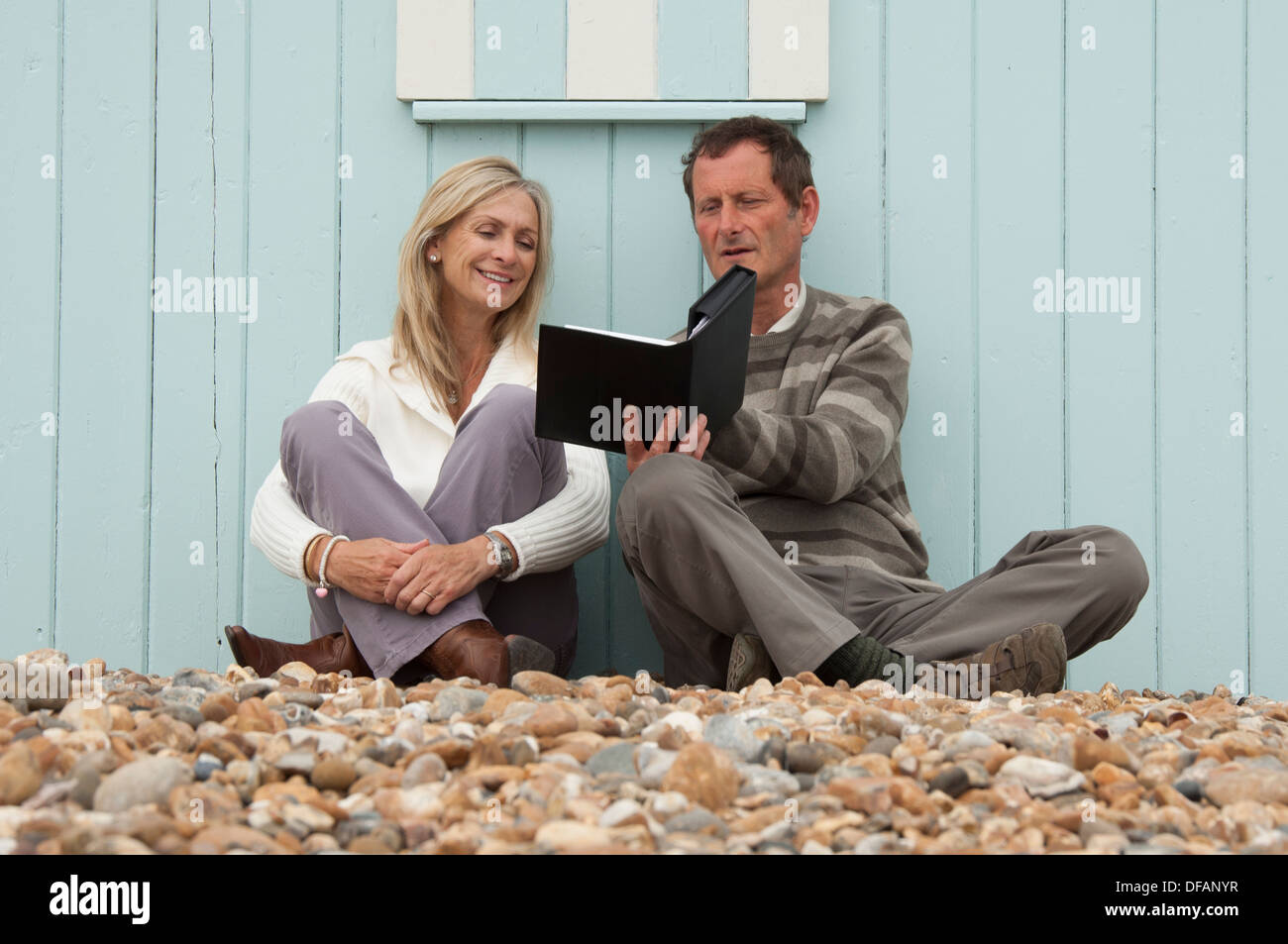 Coppia matura leggendo un libro toegether sulla spiaggia Foto Stock