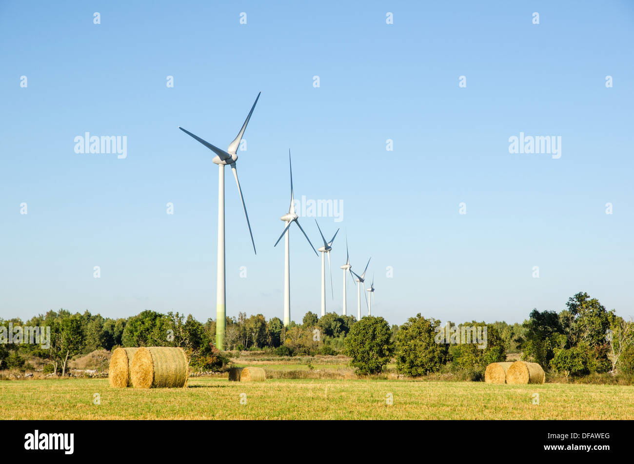 Mulini a vento in un paesaggio rurale con le balle di paglia in un campo. Foto Stock