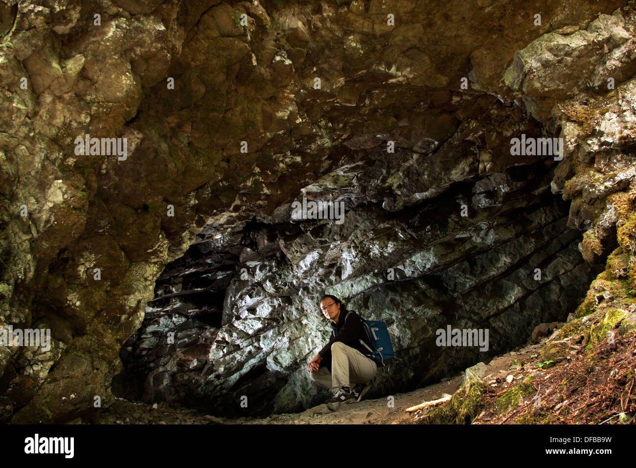 Uomo seduto in una piccola grotta di capra Creek Trail vicino Monroe, WA, Stati Uniti d'America. Foto Stock