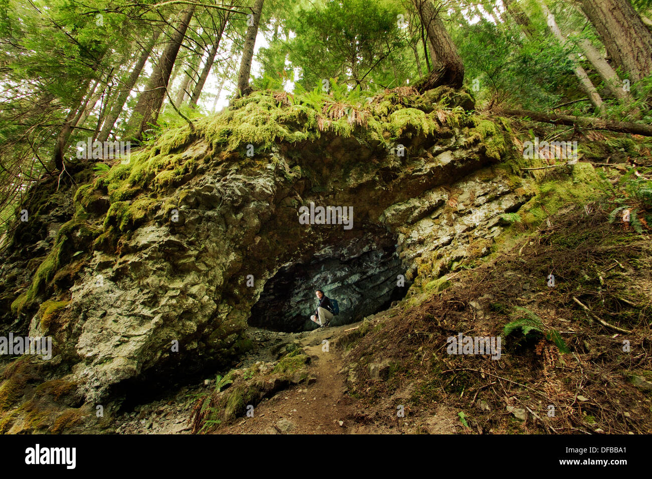 Uomo seduto in una piccola grotta di capra Creek Trail vicino Monroe, WA, Stati Uniti d'America. Foto Stock