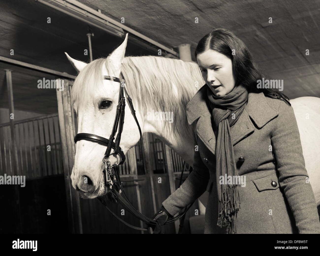 Donna conduce cavallo bianco all'interno di un fienile, formato con orizzonte di riferimento Foto Stock