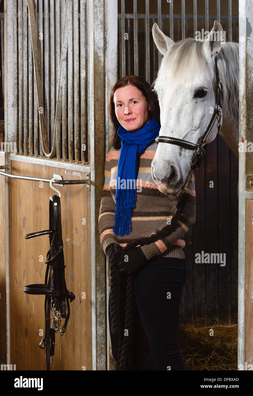 Donna e cavallo bianco all'interno di una stalla, formato verticale Foto Stock
