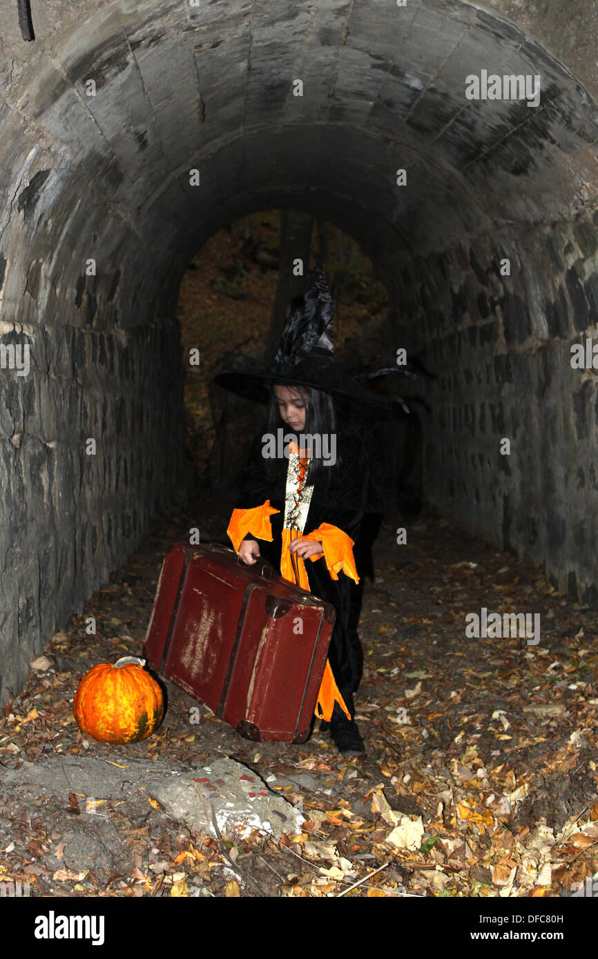 Strega bambino con una zucca e una valigia nella vigilia di Halloween Foto Stock