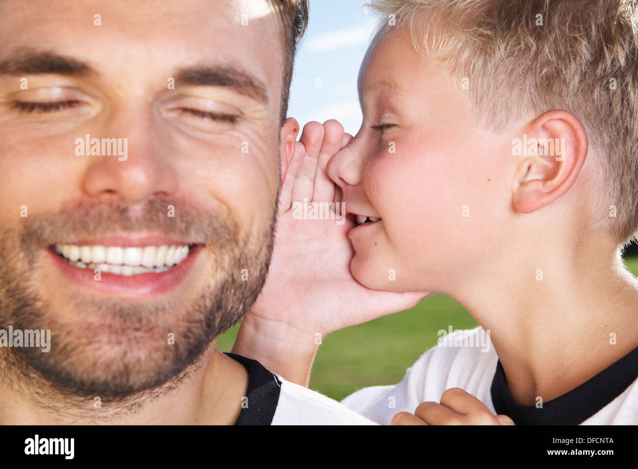 Germania, Colonia, figlio whispering in padre l orecchio Foto Stock