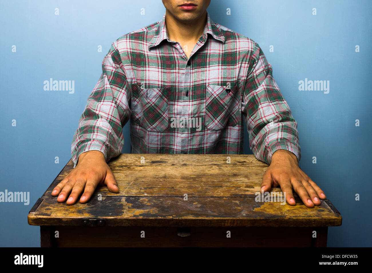 Giovane Uomo in camicia a scacchi seduta in un vecchio banco di scuola Foto Stock