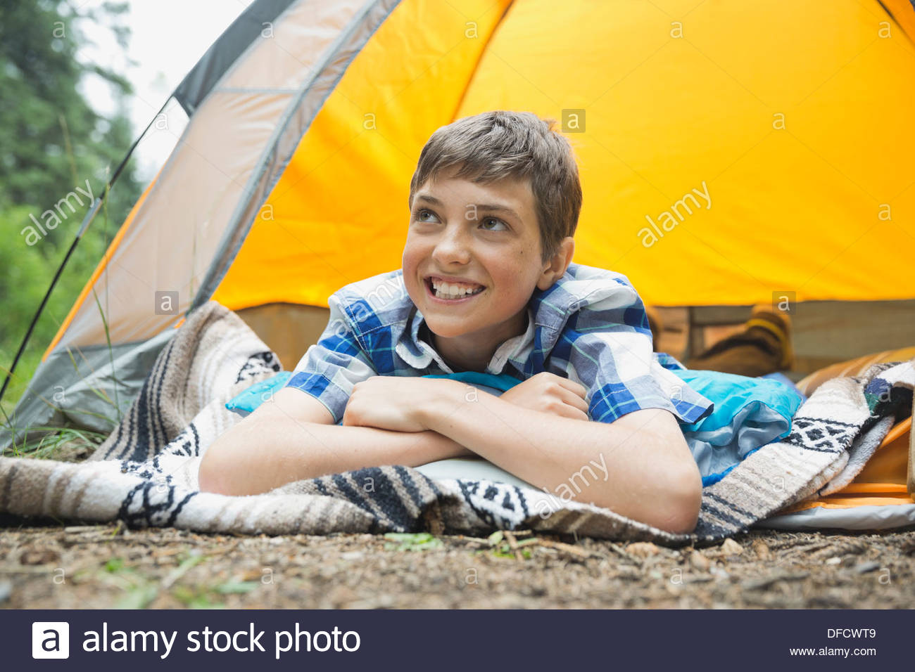 Premuroso ragazzo sorridente giacente in tenda al campeggio Foto Stock
