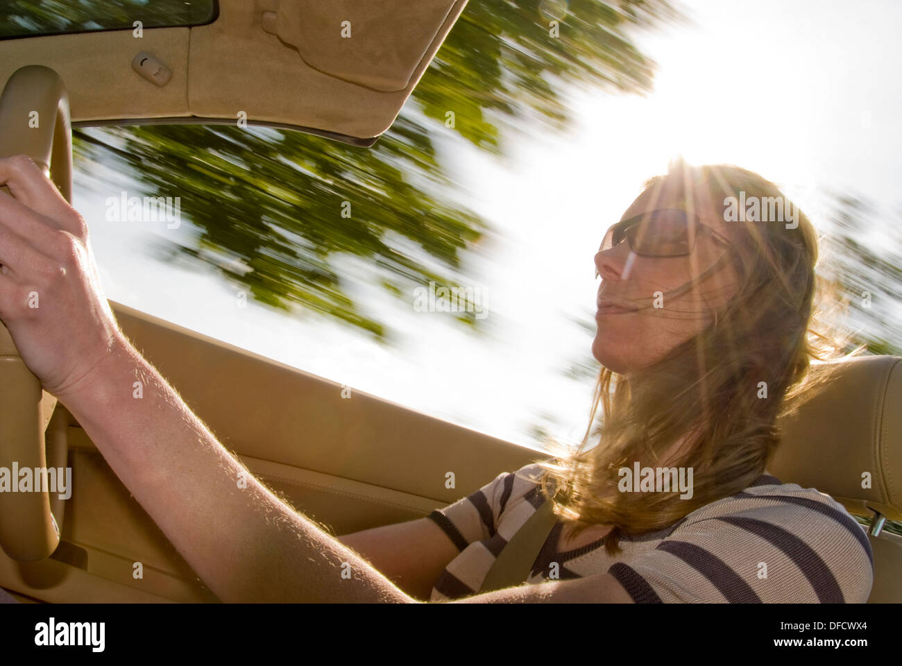 Piuttosto giovane donna, la guida a sommità aperta auto sportive in una giornata di sole, con il vento tra i capelli. Foto Stock