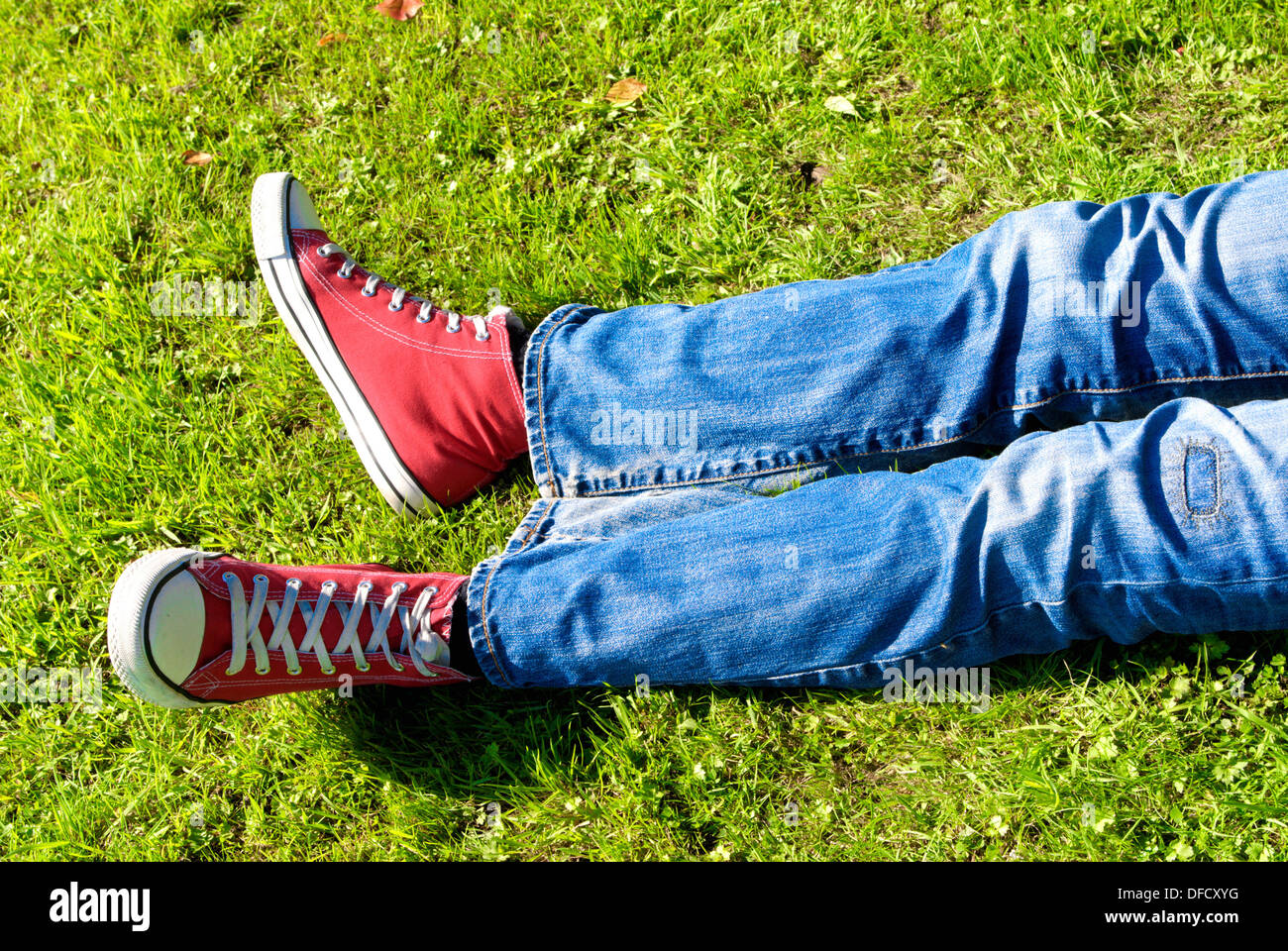 Le gambe di un giovane uomo rilassante sull'erba Foto Stock