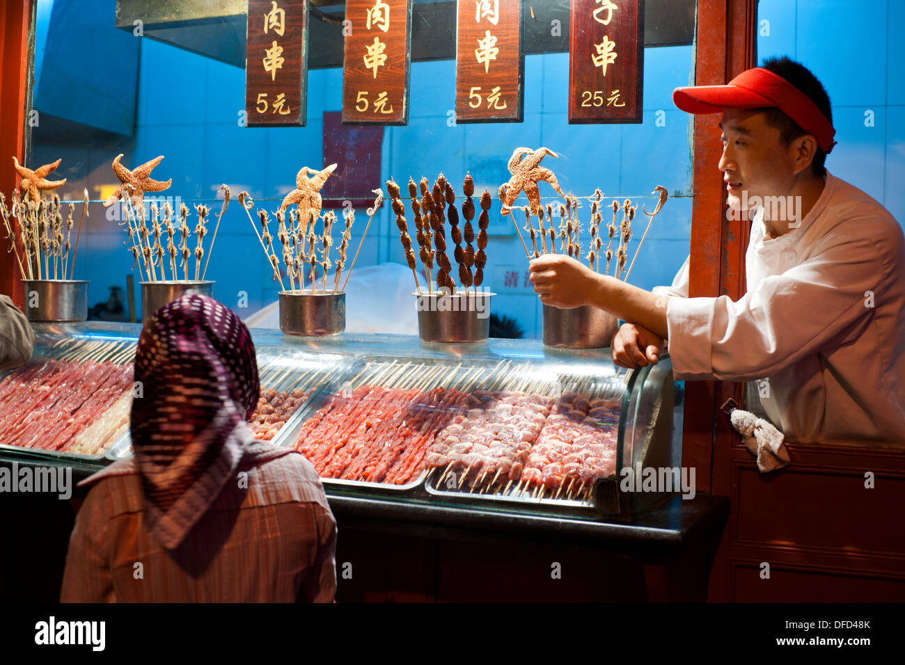 Il fornitore tiene una stella di mare su un bastone al mercato notturno Wangfujing di Pechino, Cina, Asia Foto Stock