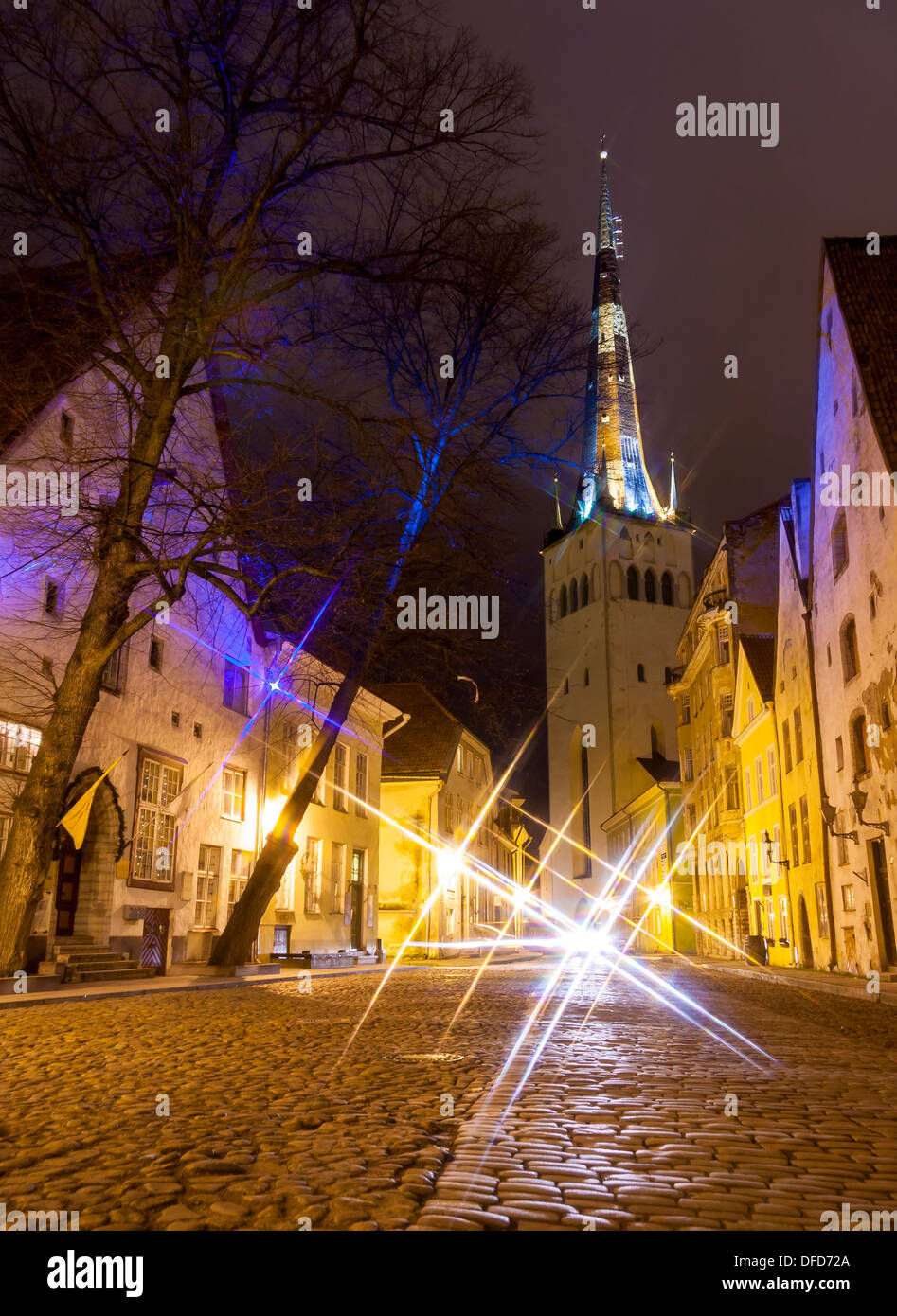 Illuminata street nella Città Vecchia di Tallinn, Estonia di notte. Chiesa di San Olaf in background. Foto Stock