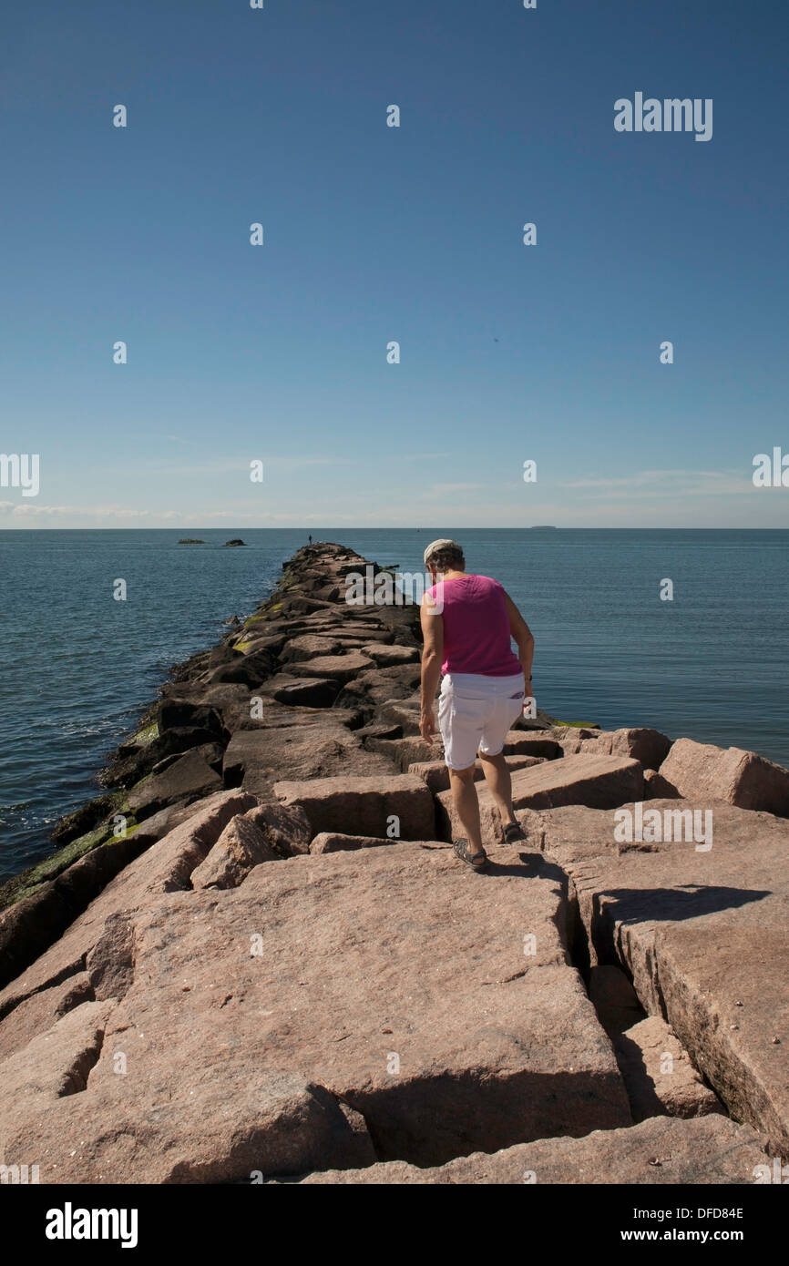 A fine estate, una donna cammina lungo il molo al Hammonasset Beach State Park, Madison, Connecticut. Foto Stock