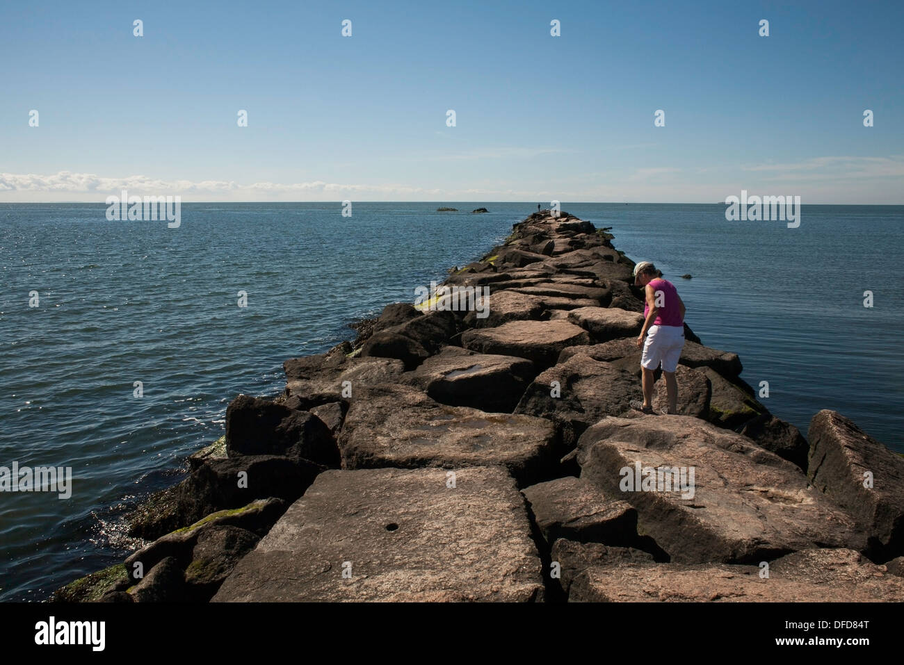 A fine estate, una donna cammina lungo il molo al Hammonasset Beach State Park, Madison, Connecticut. Foto Stock