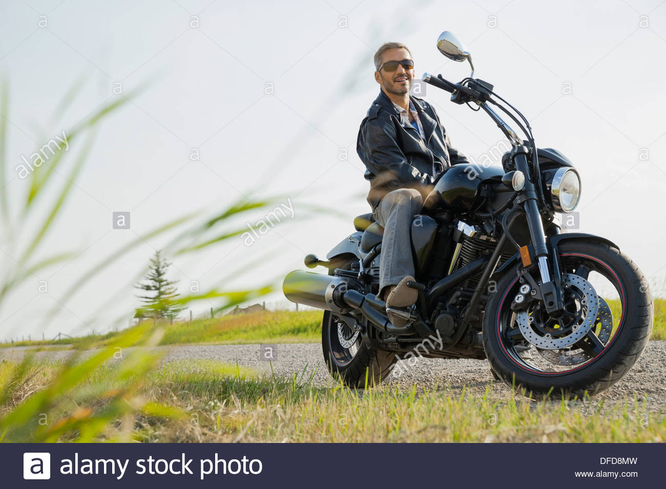 Ritratto di biker seduto sul motociclo nel paese Foto Stock