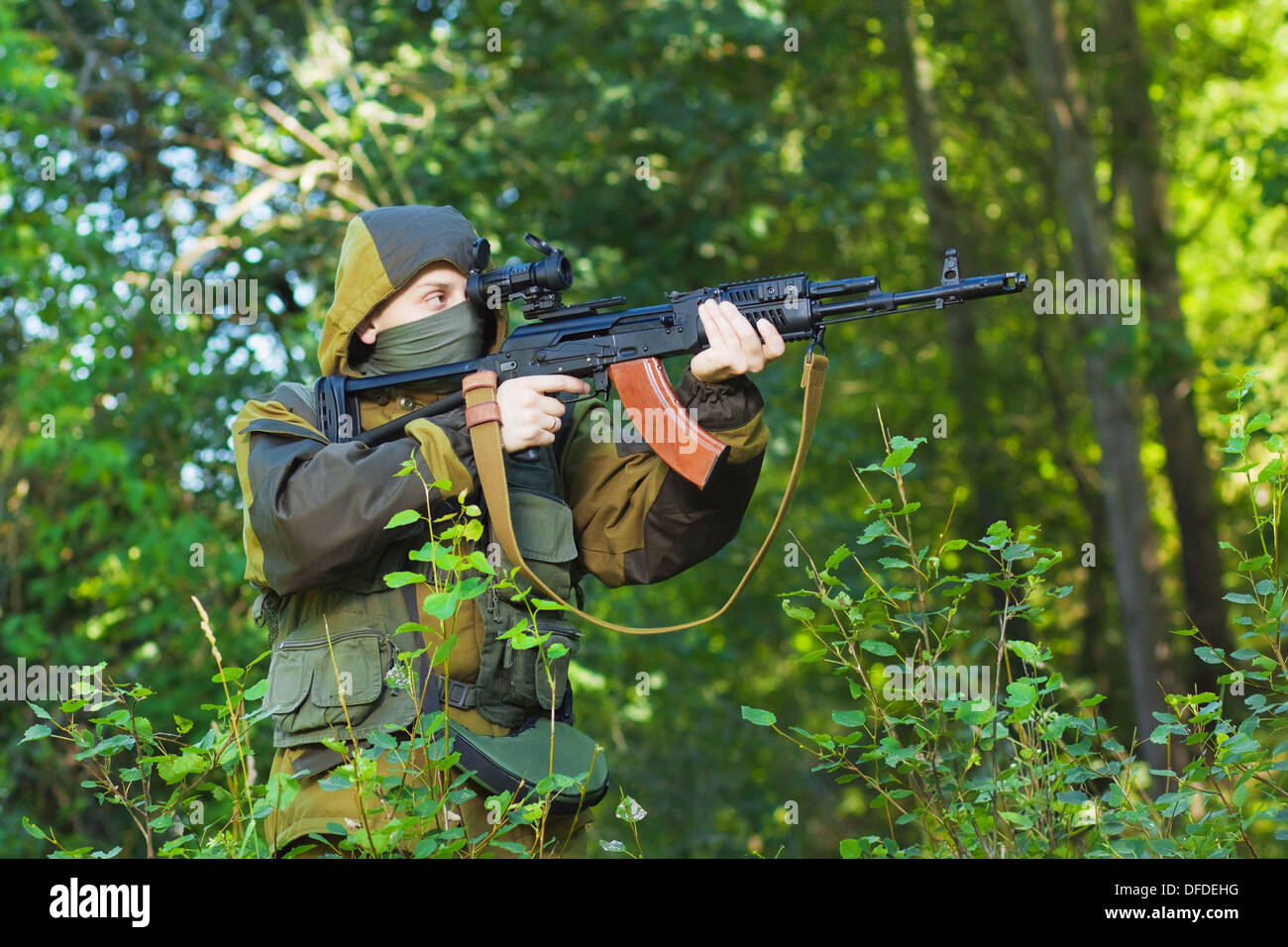 Soldato in camuffamento con un kalashnikov fucile da assalto, riprese nel bosco Foto Stock