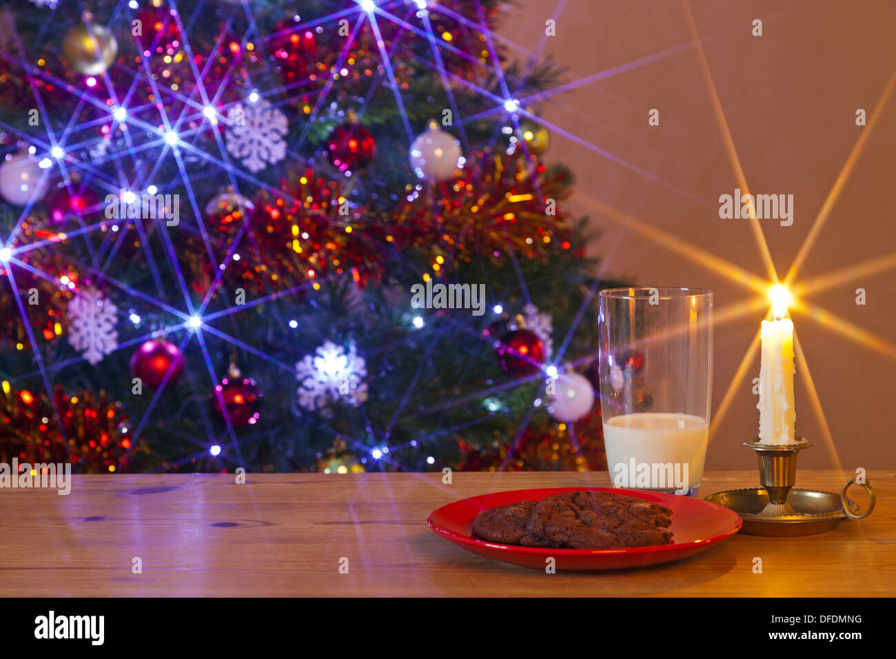 Un bicchiere di latte e biscotti a sinistra per Santa Claus in una tabella nella parte anteriore dell'albero di Natale Foto Stock