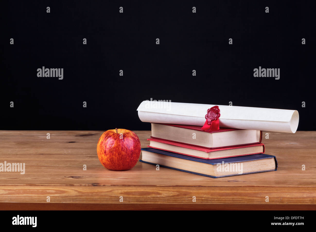 Banco di scuola con libri e un diploma contro uno sfondo nero, aggiungi il proprio testo. Foto Stock