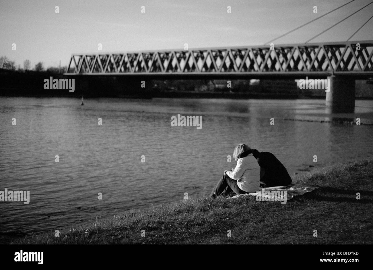 Giovane seduto sulla sponda del fiume Reno Maxau Karlsruhe in Germania Foto Stock