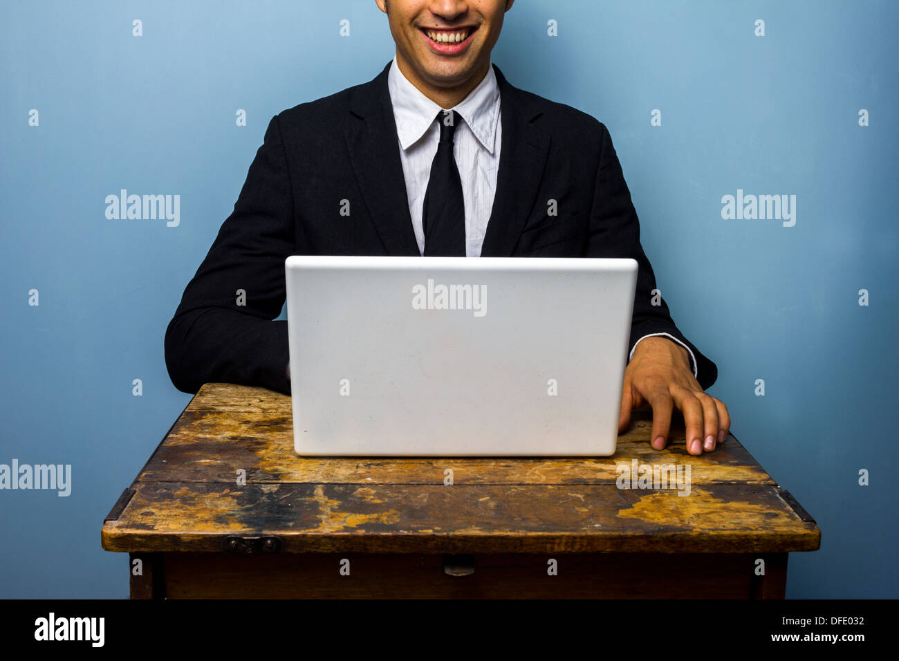 Felice giovane imprenditore è seduta su una vecchia scrivania un lavoro sul suo computer Foto Stock