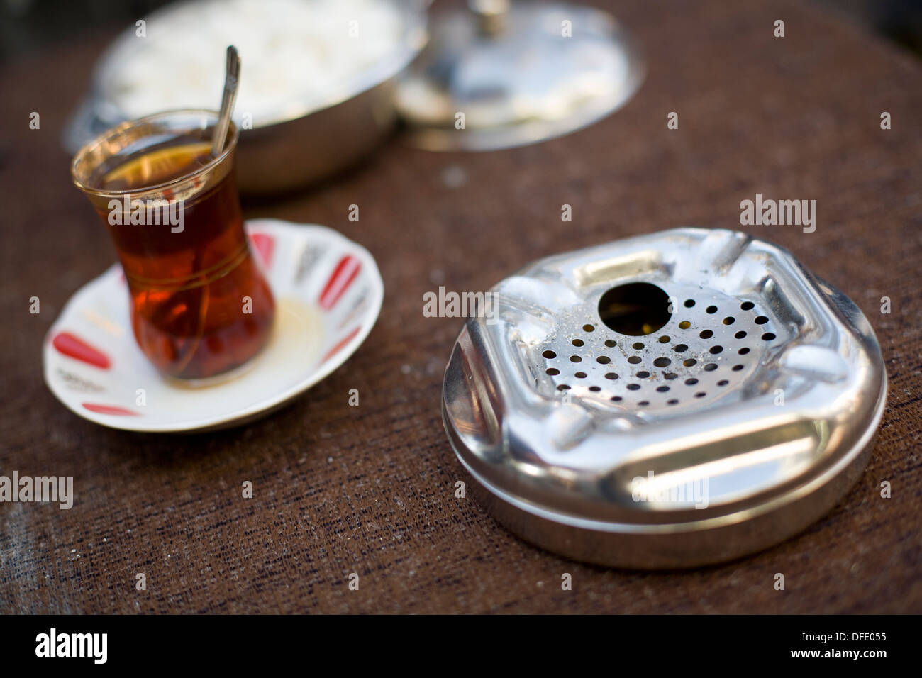 Close-up di un posacenere cromato e bicchiere di tè su un tavolo in un caffè di Istanbul, Turchia. Foto Stock
