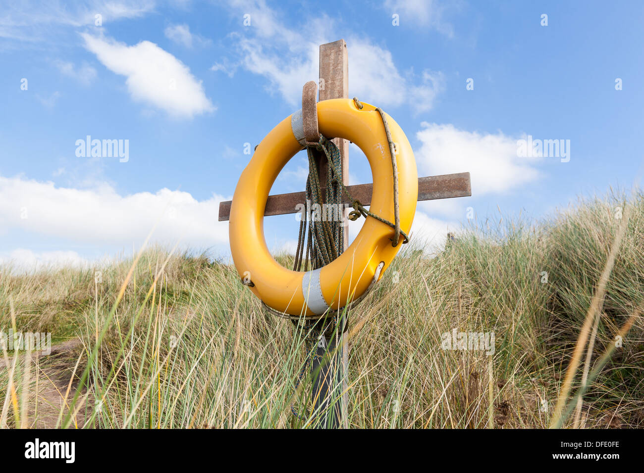 Un salvagente giallo su un supporto di legno nelle dune su una spiaggia nel Devon, in Inghilterra. Formato orizzontale. Foto Stock