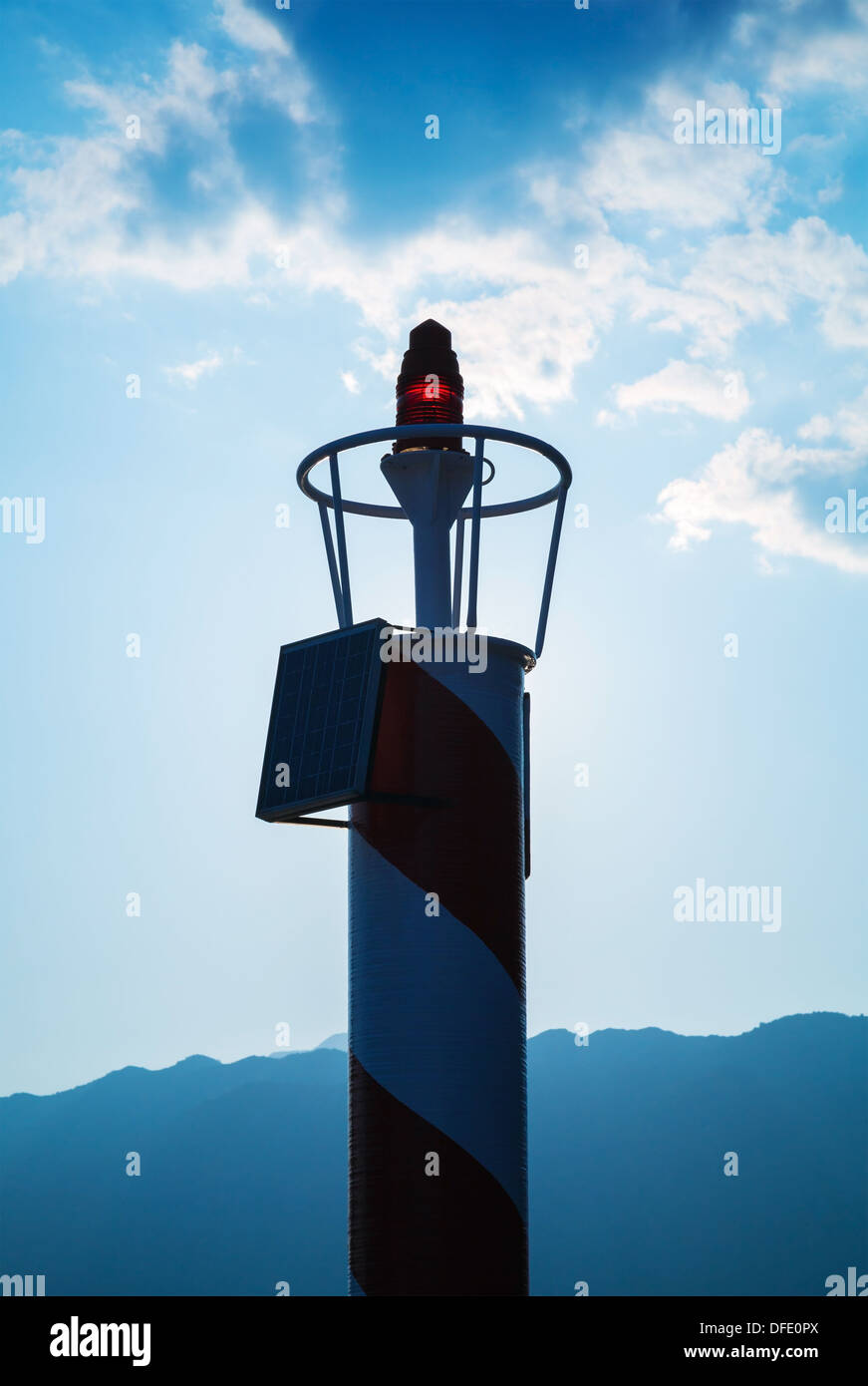 Piccolo faro rosso sopra lanterna blu scuro cielo molto nuvoloso Foto Stock