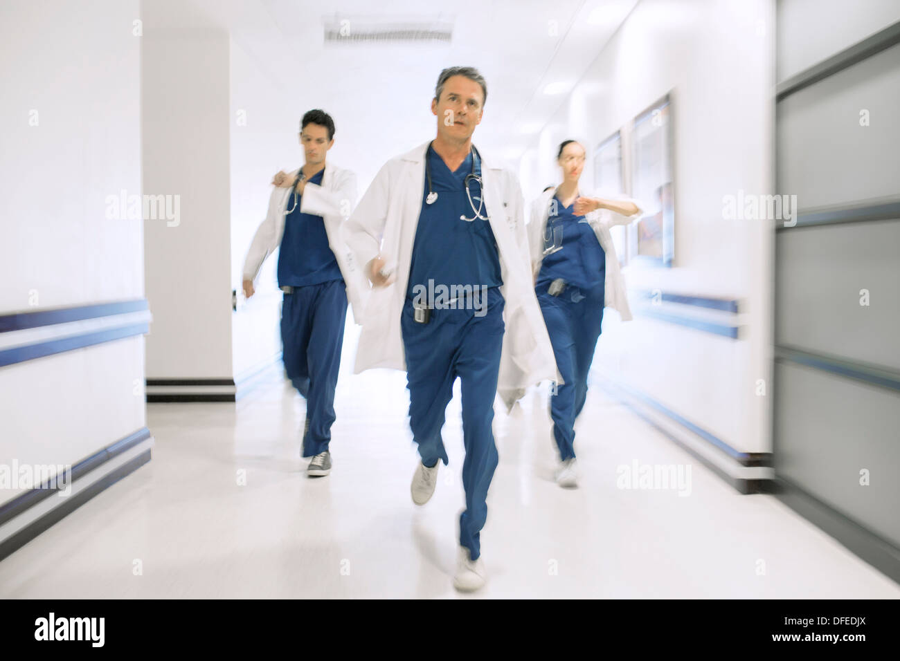I medici correre verso il basso corridoio ospedale Foto Stock