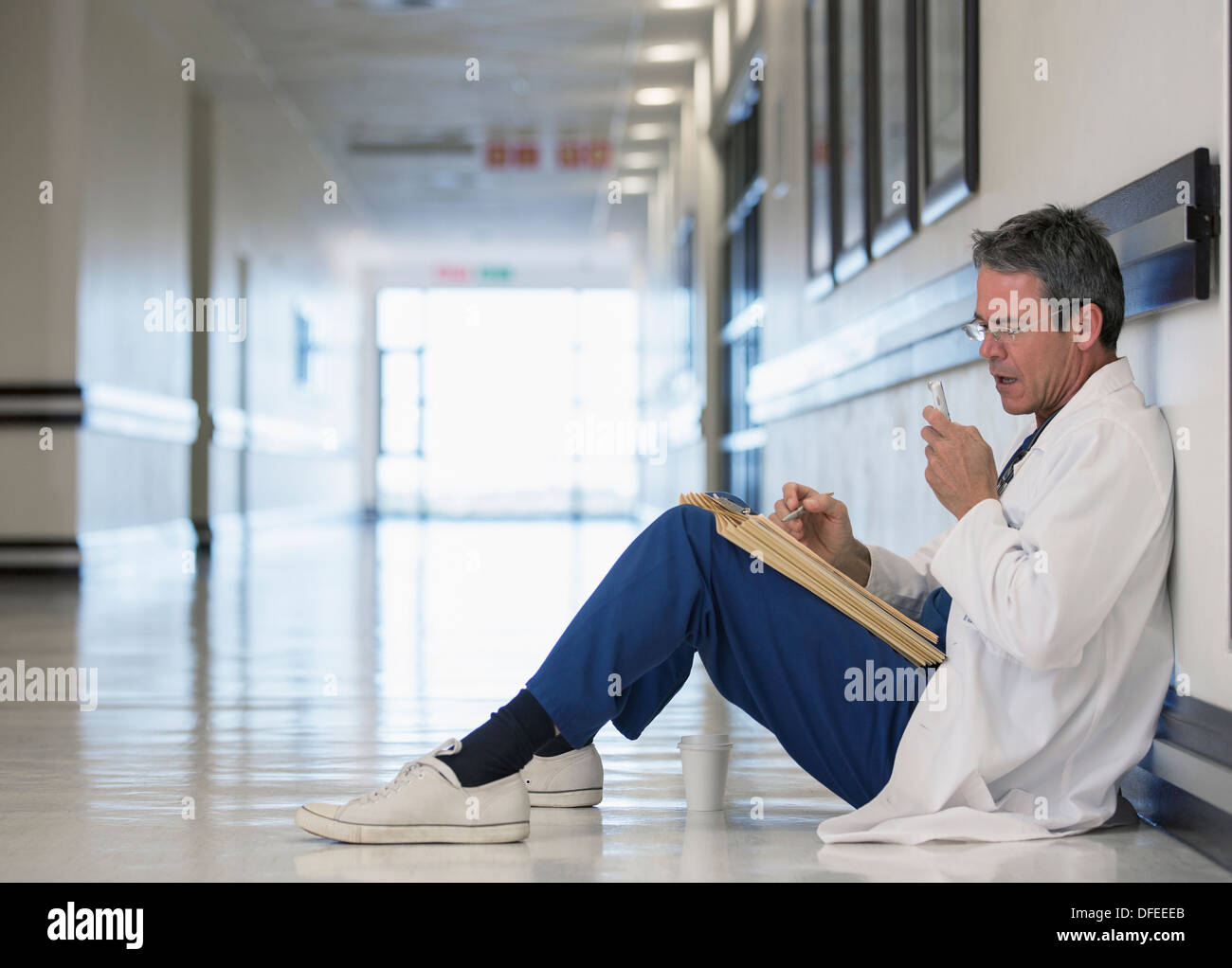 Medico utilizzando dictaphone nel corridoio di ospedale Foto Stock