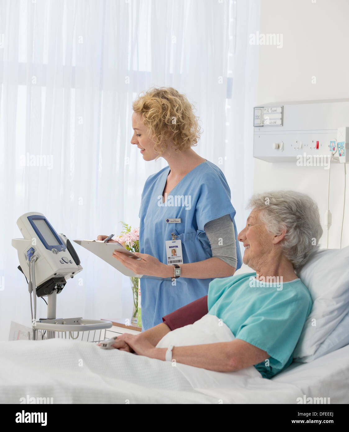 L'infermiera apparecchiature di controllo in invecchiamento del paziente stanza di ospedale Foto Stock