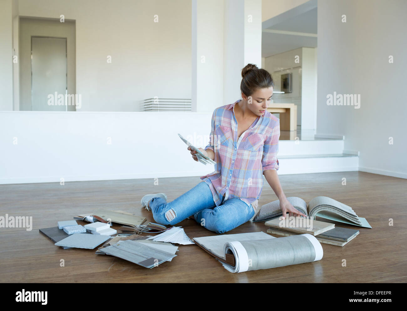 La donna la visualizzazione di moquette e campioni di piastrelle sul pavimento nella nuova casa Foto Stock