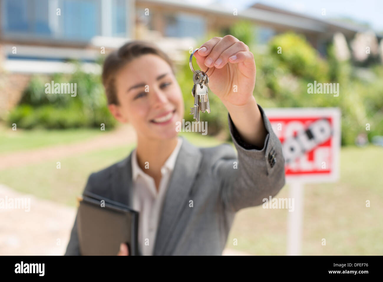 Ritratto di agente immobiliare tenendo le chiavi di casa di fronte a casa Foto Stock