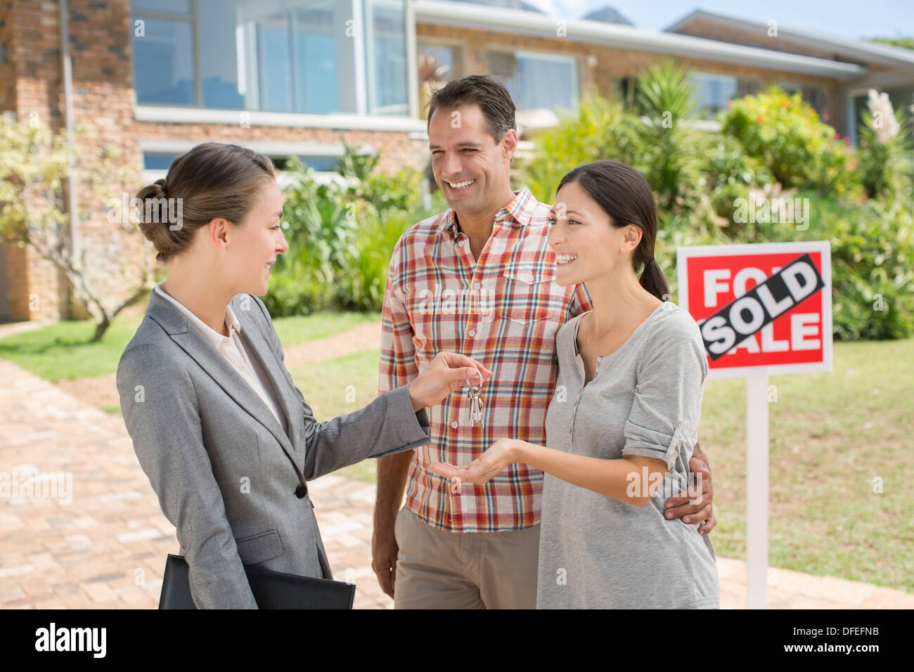 Agente immobiliare dando giovane le chiavi di casa nuova Foto Stock