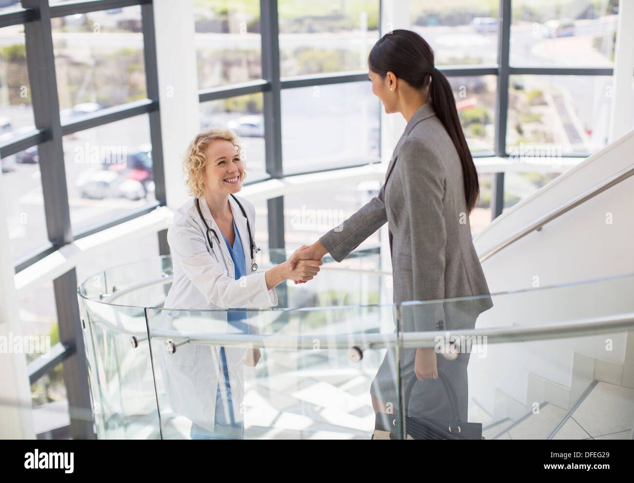 Medico e imprenditrice handshaking su scale in ospedale Foto Stock