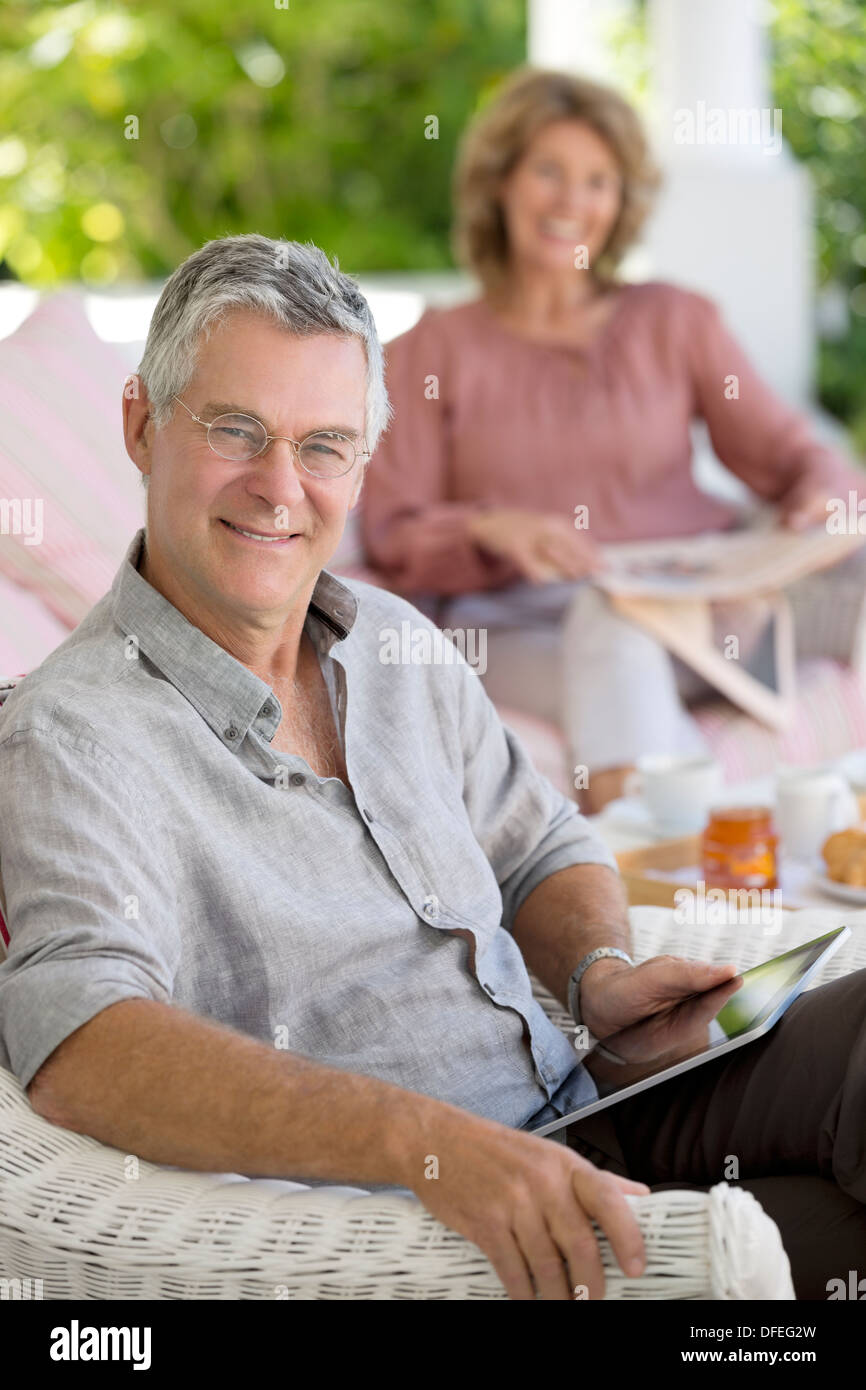 Senior uomo con tavoletta digitale in poltrona sul patio Foto Stock