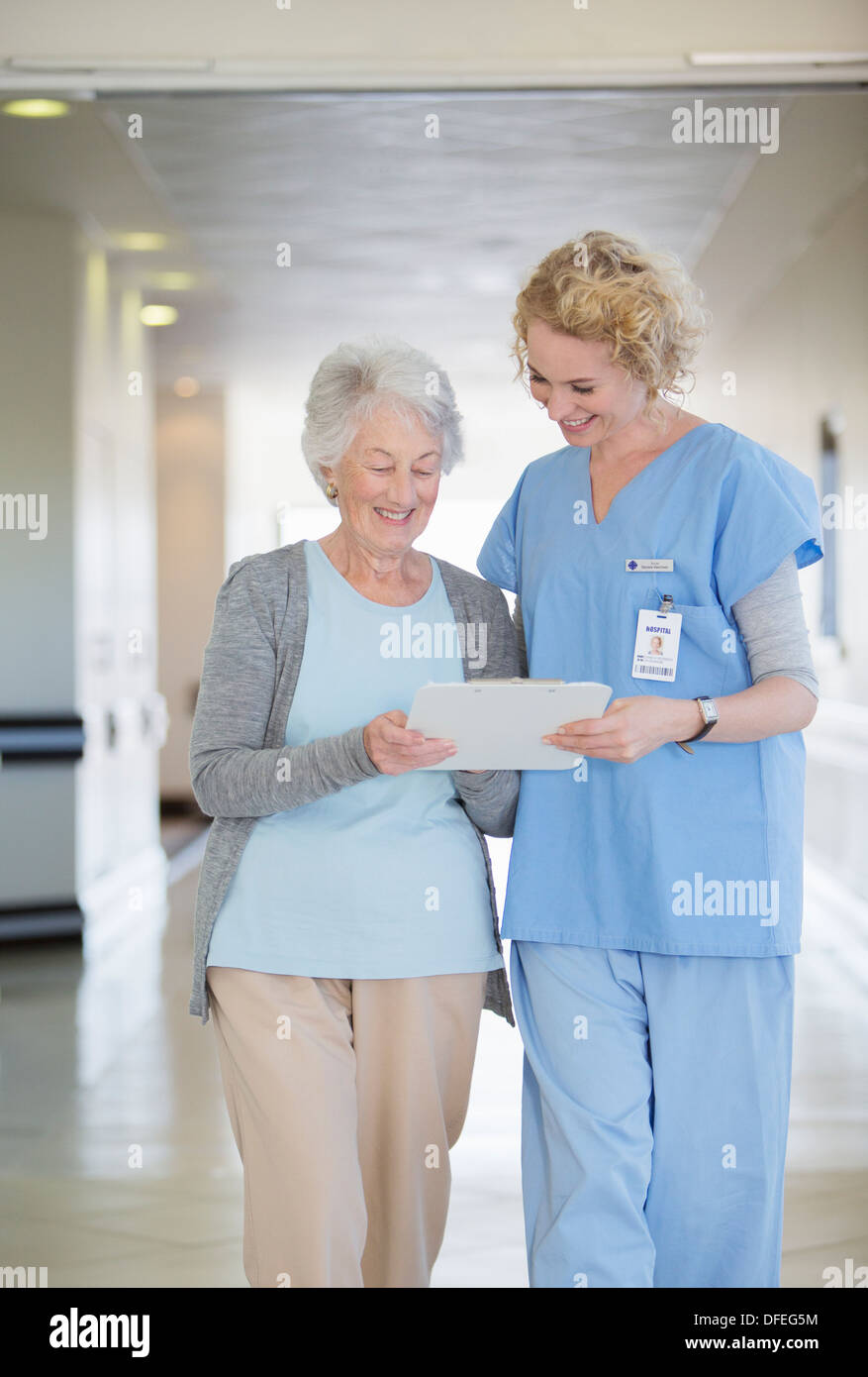 Infermiera e paziente invecchiamento grafico di lettura in ospedale corridoio Foto Stock