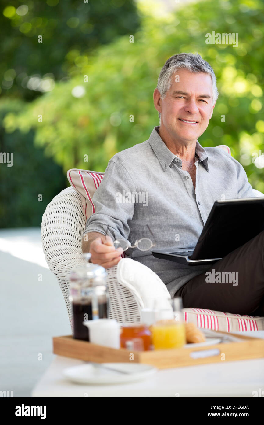 Senior uomo utilizzando laptop sul patio Foto Stock