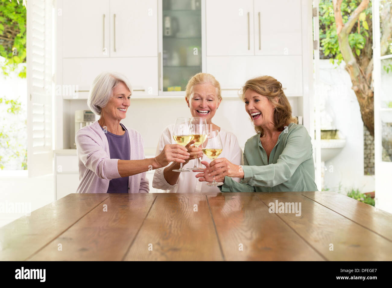 Le donne anziane tostatura di bicchieri di vino in cucina Foto Stock