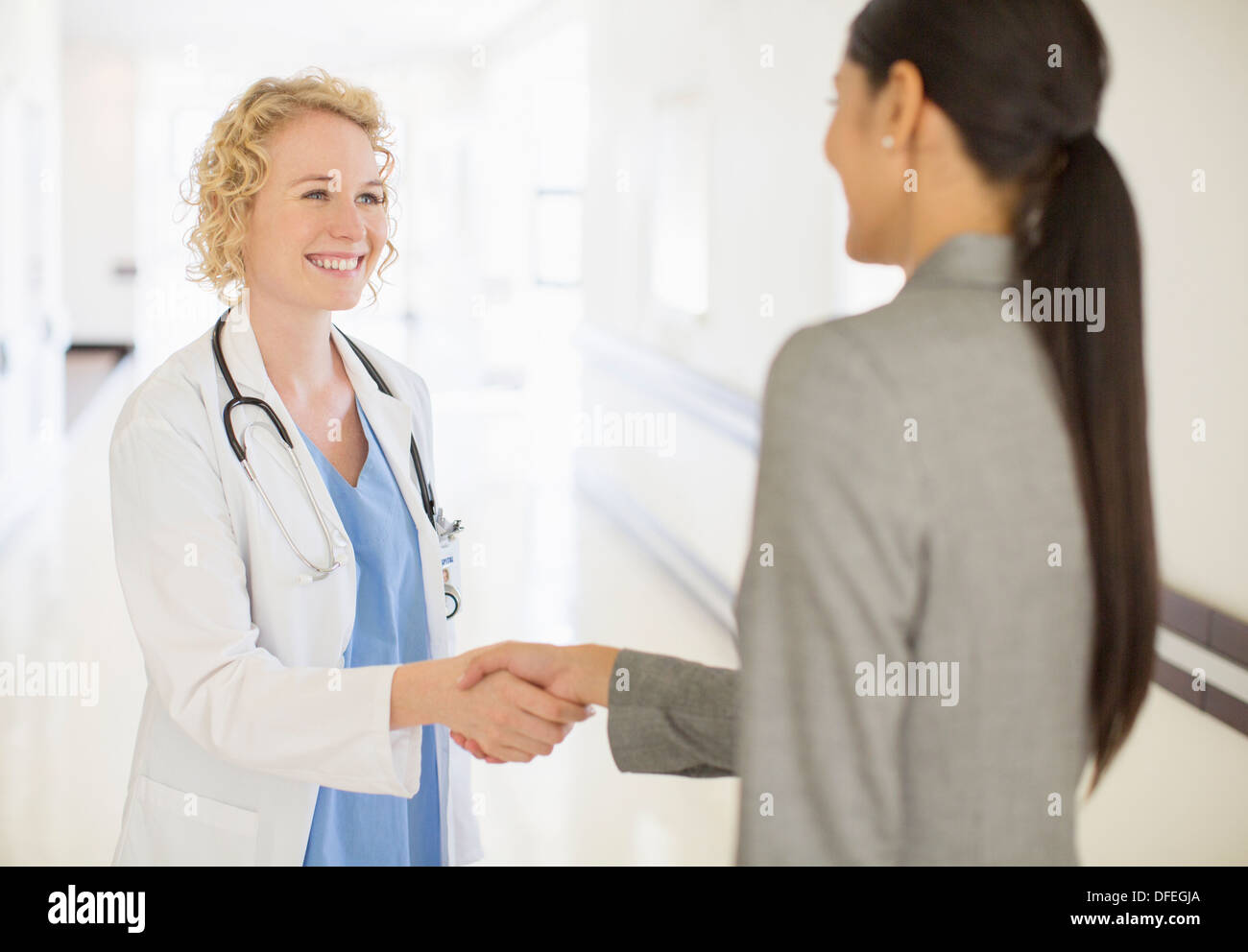 Medico e imprenditrice di handshaking ospedale in corridoio Foto Stock