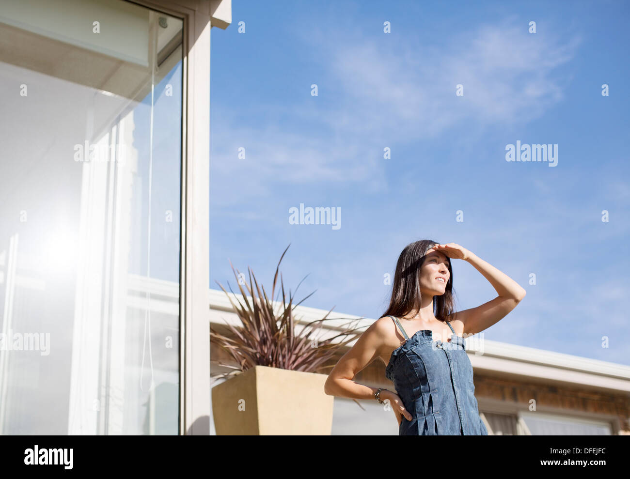 La donna gli occhi di schermatura al di fuori di casa moderna Foto Stock