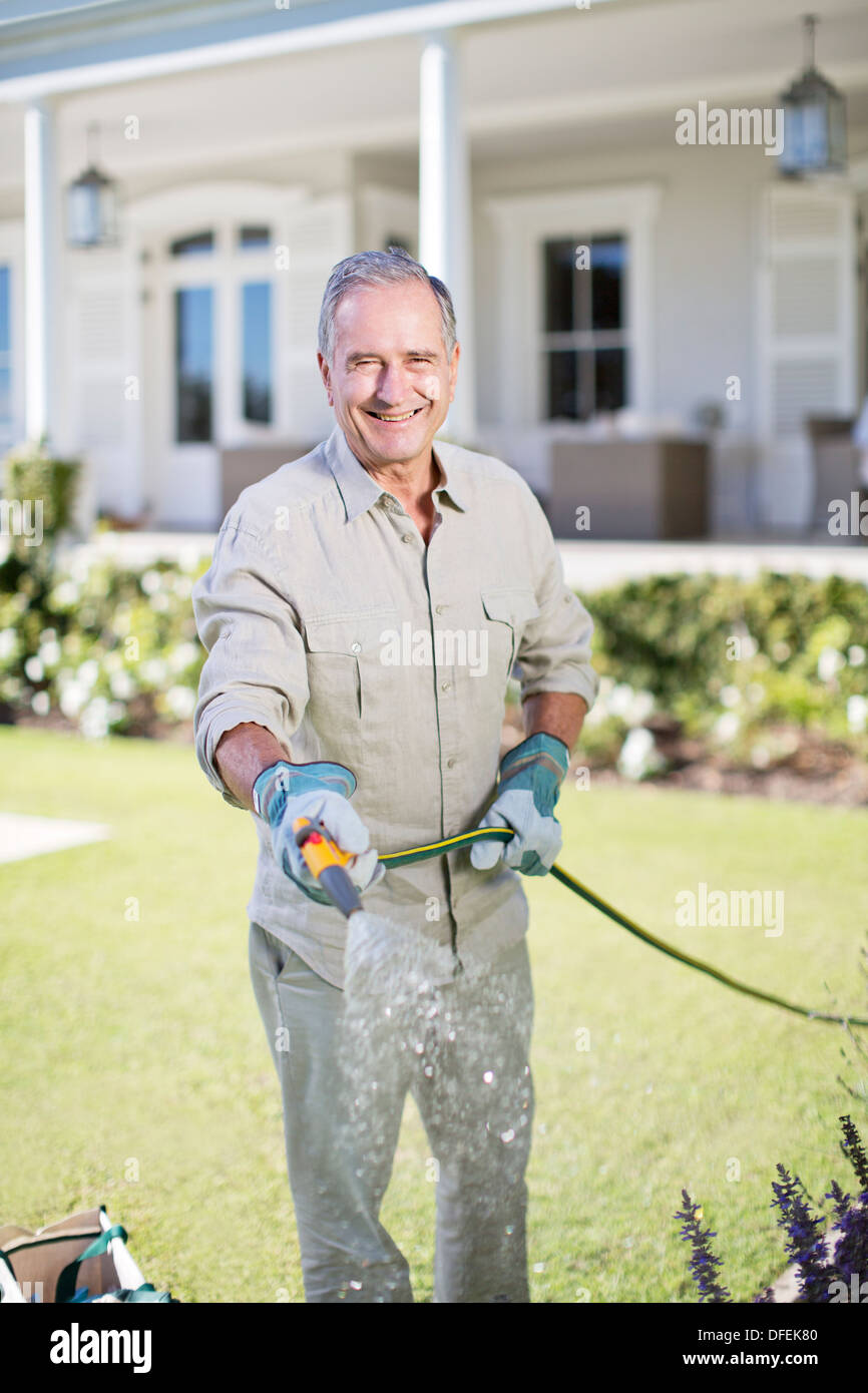 Uomo senior di impianti di irrigazione in giardino Foto Stock